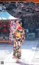 A woman in a kimono standing in front of a temple.