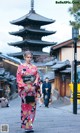 A woman in a kimono standing in front of a pagoda.