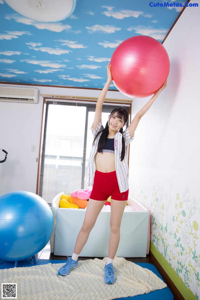 A woman holding a large pink ball in a room.