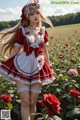 A woman in a red and white dress standing in a field of roses.