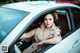 A woman sitting in the driver's seat of a white car.