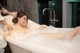 A woman taking a bath in a bathtub with foam.