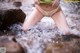 A woman in a yellow bikini is standing in a stream.