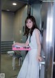 A woman in a white dress holding a pink box.