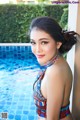 A woman in a colorful bikini posing by a swimming pool.