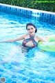 A woman in a bikini floating in a swimming pool.