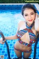 A woman in a colorful bikini standing next to a swimming pool.