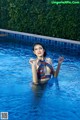 A woman in a bikini standing in a swimming pool.