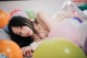 A woman laying on top of a pile of colorful balloons.