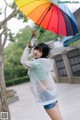 A woman holding a colorful umbrella in the rain.