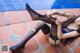 A woman in black stockings and a blue bra is laying on the ground.