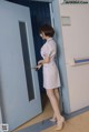 A woman in a white dress is opening a door.