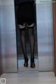 A woman in black stockings and high heels standing in an elevator.