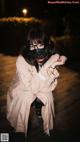 A woman wearing a face mask sitting on a wooden floor.