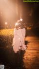 A woman wearing a mask standing on a boardwalk at night.