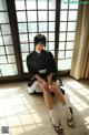 A woman in a black kimono sitting on the floor.