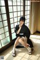 A woman in a black kimono sitting on the floor.