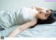 A woman laying on top of a bed in a white shirt.