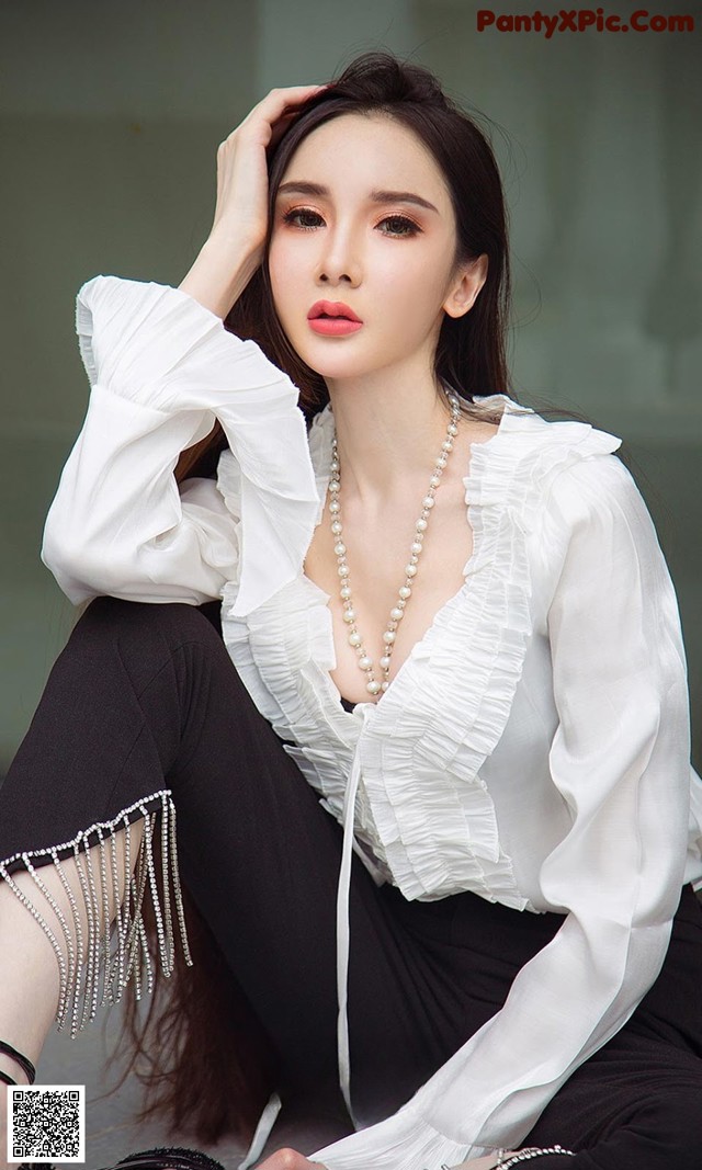 A woman wearing a white blouse and black pants.