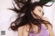 A woman laying on a bed with her hair blowing in the wind.